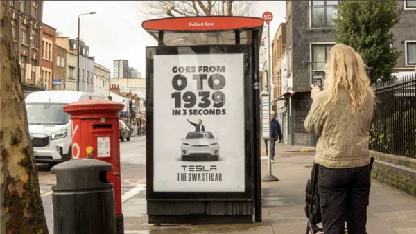Woman takes a photo of a poster that says "goes from 0 to 1939 in 3 seconds - Tesla, the Swasticar"